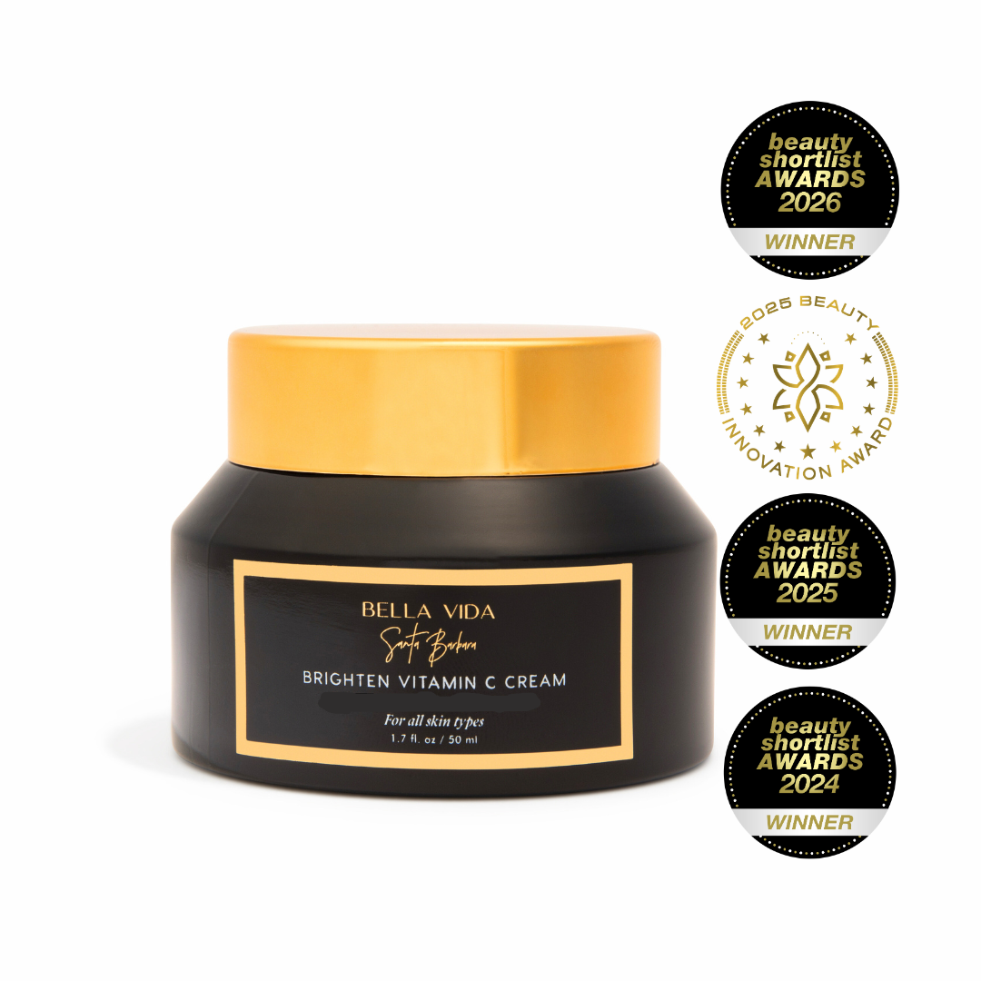 Black jar of Bella Vida Brighten Vitamin C Cream with gold lid on a white background, featuring multiple awards.